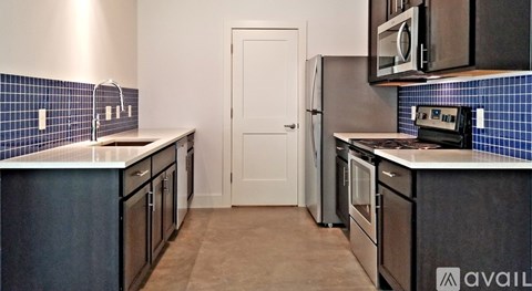A kitchen with black cabinets and a white door.