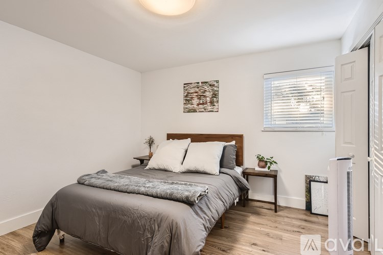 A bedroom with a bed, nightstand, and window.