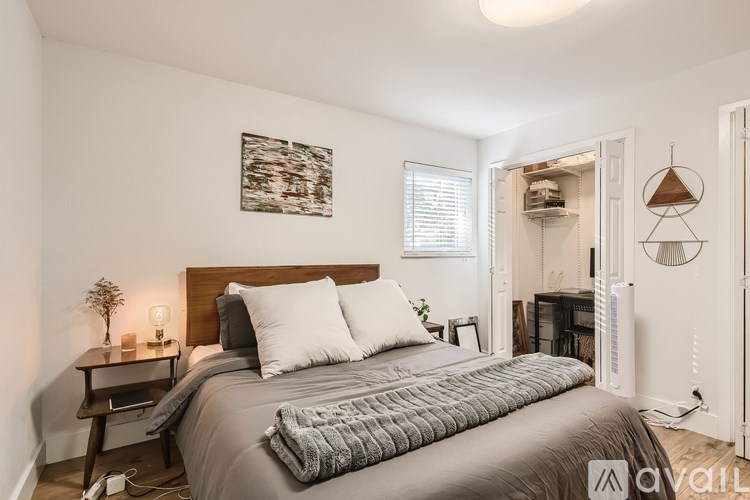 A bedroom with a large bed and a small table with a plant on it.