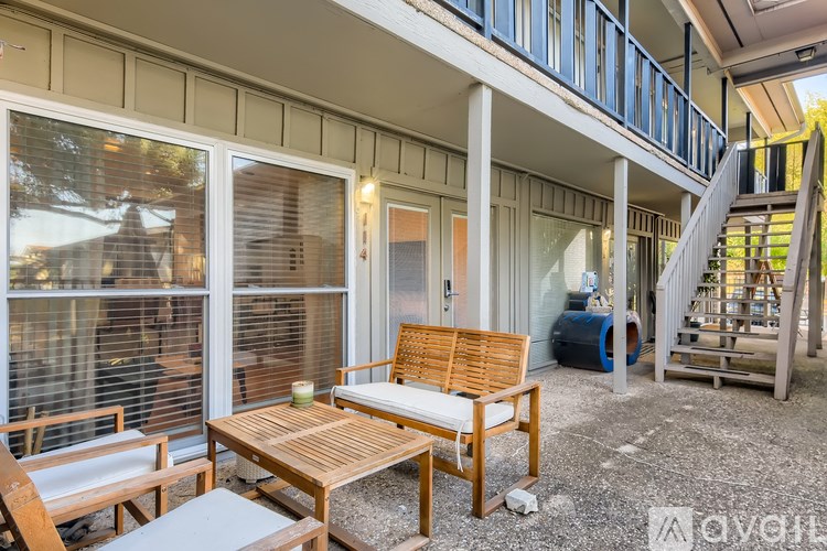 A wooden table and chairs are on a patio with a staircase in the background.