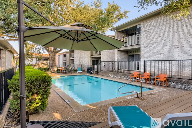 A pool with a sun shade and chairs around it.