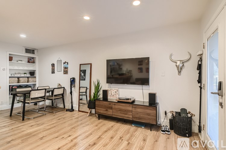 A living room with a TV, a wooden cabinet, and a dining table.