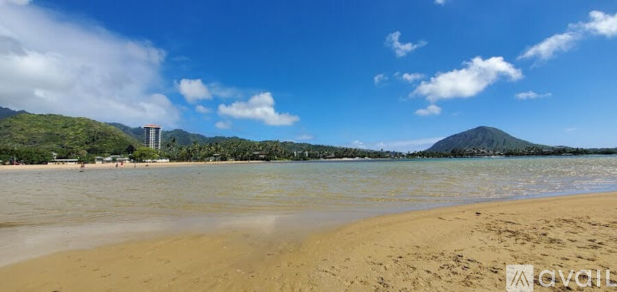 A beach with a mountain in the distance and a building on the left side.