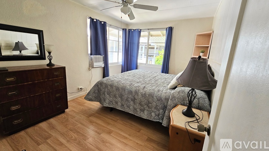 A bedroom with a bed, dresser, and a ceiling fan.