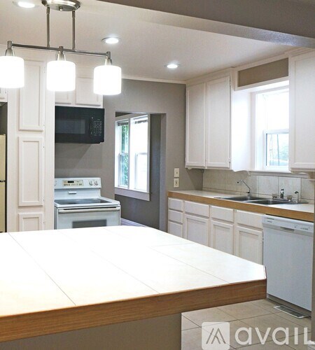 A kitchen with white cabinets and a wooden island.