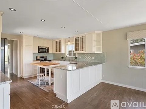 A kitchen with white cabinets and a wooden island.