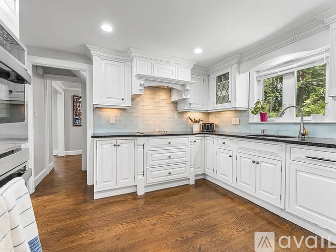 A kitchen with white cabinets and a wooden floor.