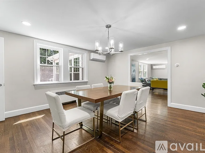A dining room with a wooden table and white chairs.