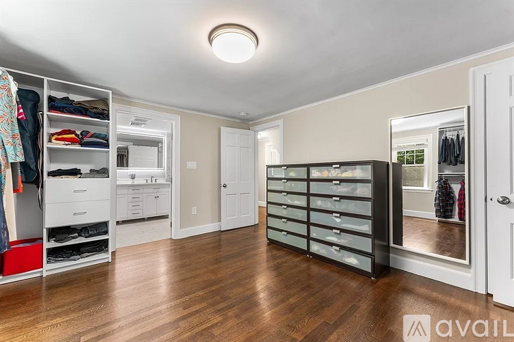 A spacious walk-in closet with wooden floors and white walls.