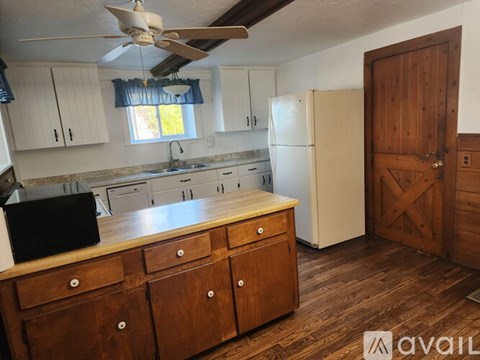 A kitchen with wooden floors and a white fridge.