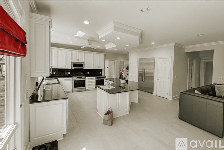A modern kitchen with white cabinets and black countertops.