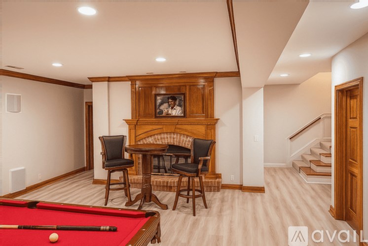 A pool table is in the middle of a room with a fireplace and chairs.