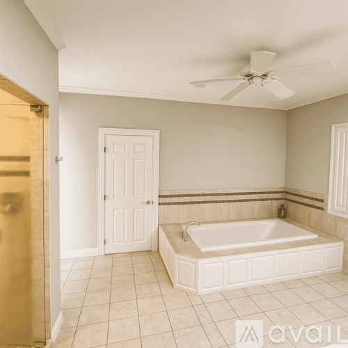 A bathroom with a white tub and a ceiling fan.
