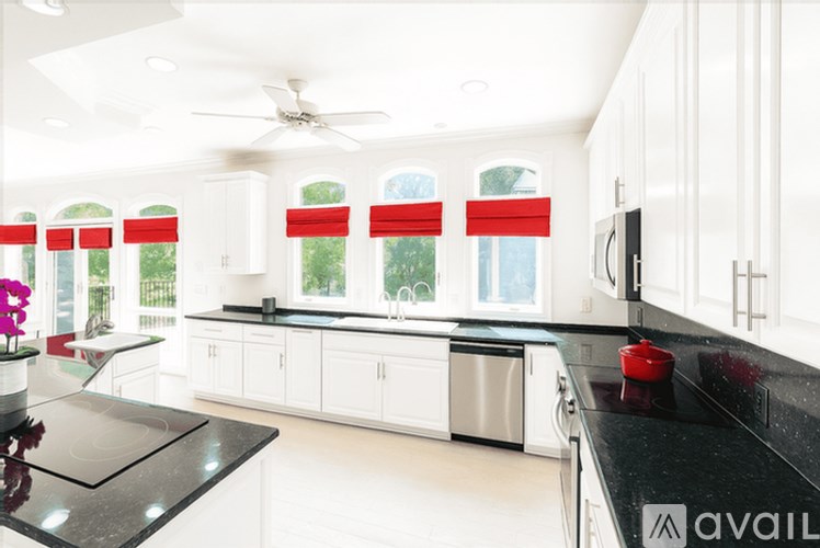 A modern kitchen with white cabinets and a black countertop.
