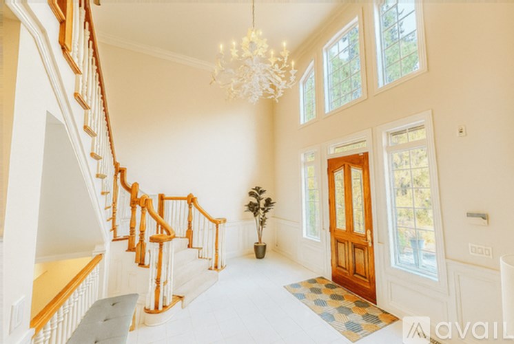 A large, well-lit foyer with a staircase and a chandelier.