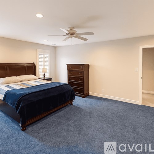 A bedroom with a bed, dresser, and ceiling fan.