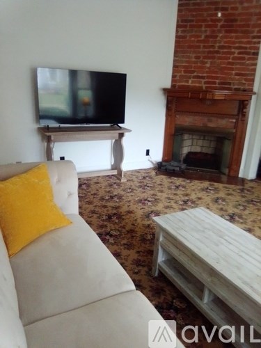 A living room with a white couch and a television on a stand.