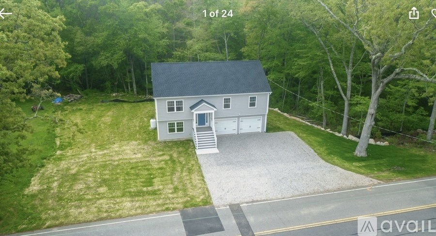 A house with a gravel driveway is surrounded by trees.