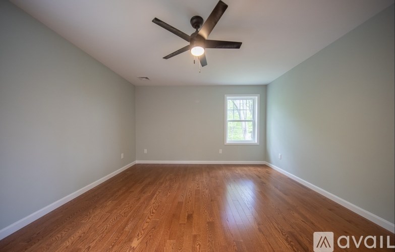 A room with a ceiling fan and wooden flooring.