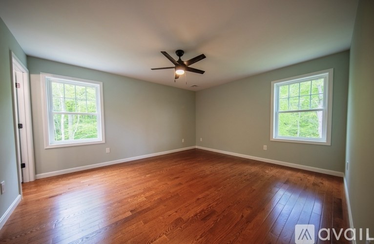 A room with a ceiling fan and two windows.