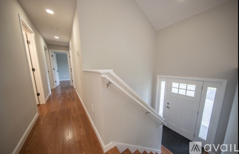 A long hallway with a staircase on the right and a door at the end.