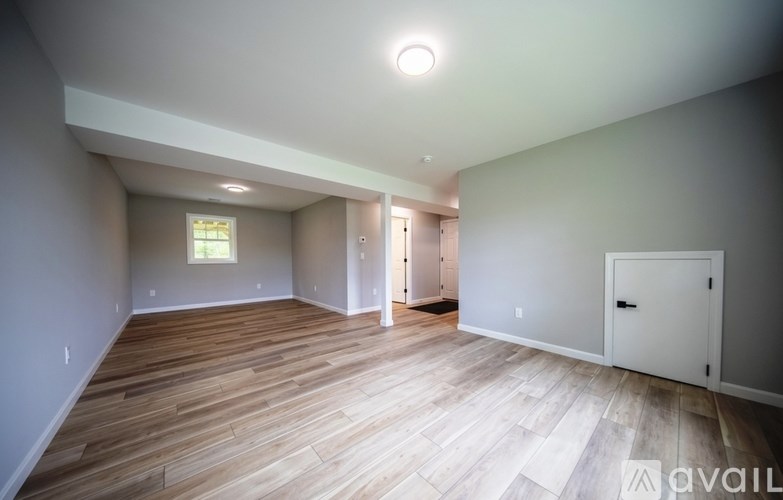 A spacious room with wooden flooring and white walls.