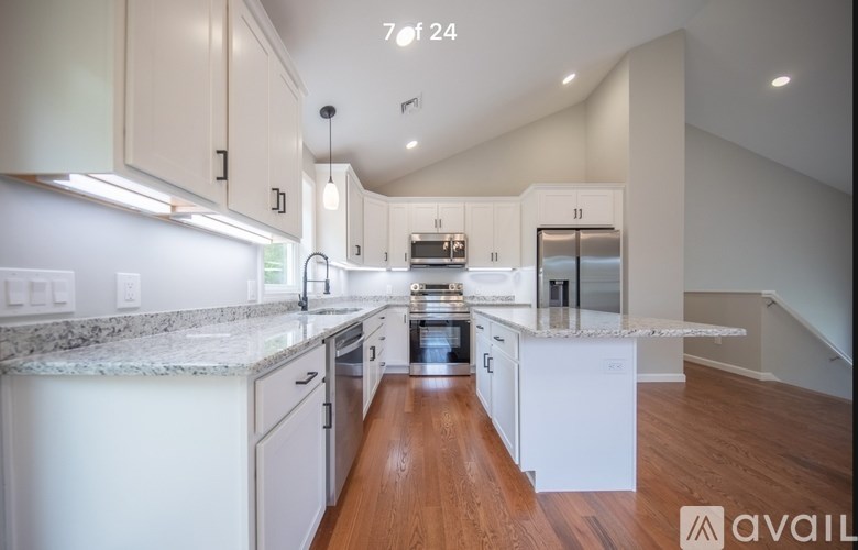 A modern kitchen with white cabinets and a marble countertop.