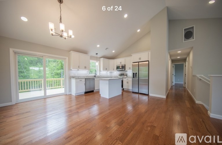 A spacious kitchen with white cabinets and a wooden floor.
