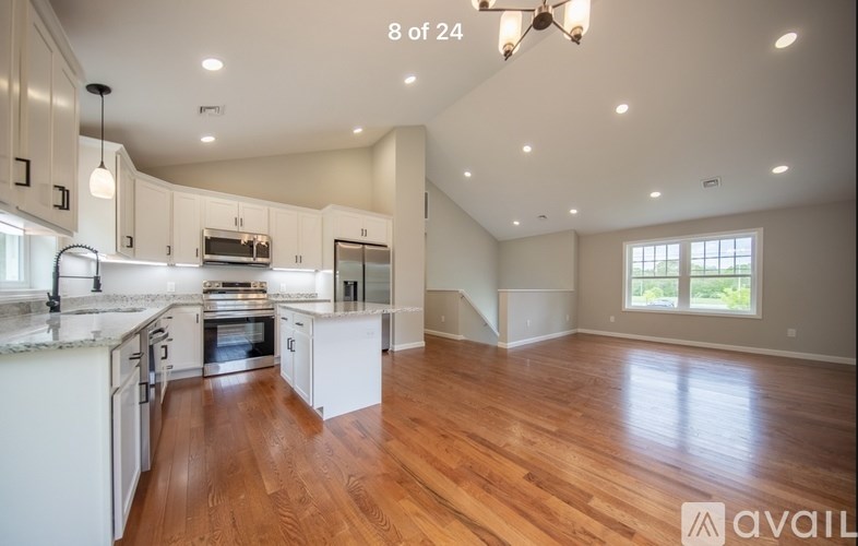 A spacious kitchen with white cabinets and a wooden floor.