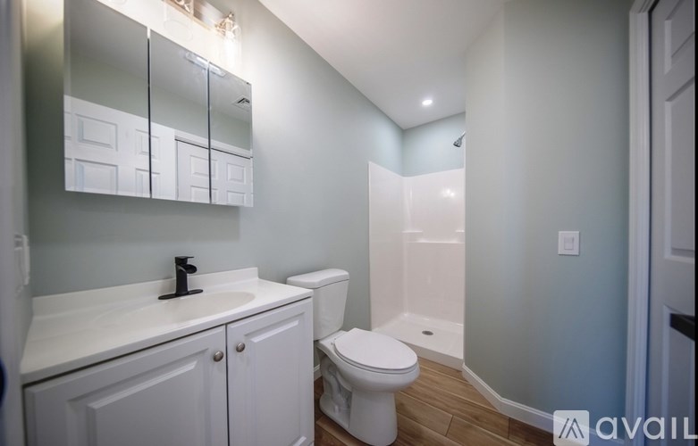 A white toilet sits in a bathroom with a white sink and a white cabinet.