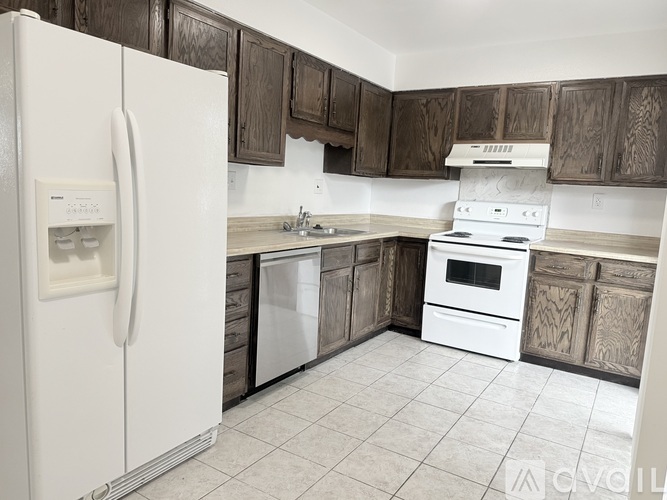 A kitchen with a white refrigerator, white stove, and wooden cabinets.