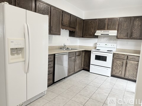 A kitchen with a white refrigerator, white stove, and wooden cabinets.