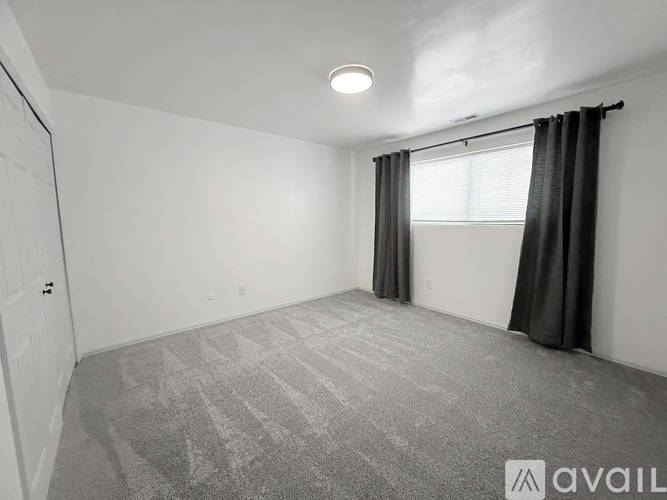 A room with a carpeted floor and a window with curtains.
