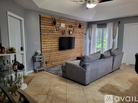 A living room with a grey couch and a wooden wall.