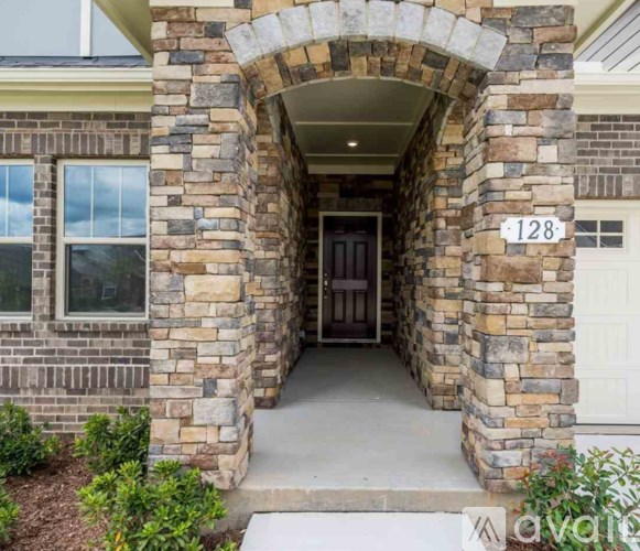 A stone archway leads to the front door of a house numbered 128.