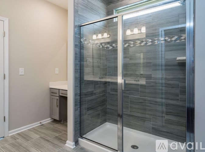 A modern bathroom with a walk-in shower and a white sink.