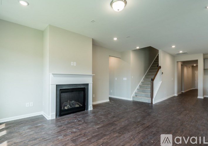 A spacious living room with a fireplace and a staircase.