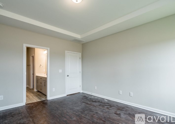 A room with a white door and a brown floor.