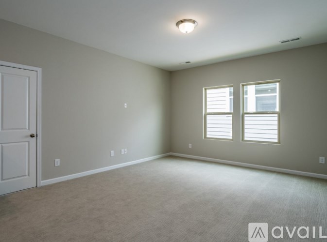 A room with a door, two windows, and a carpeted floor.