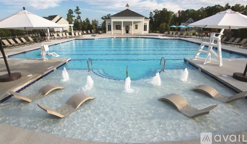 A pool with a fountain in the middle and lounge chairs around it.