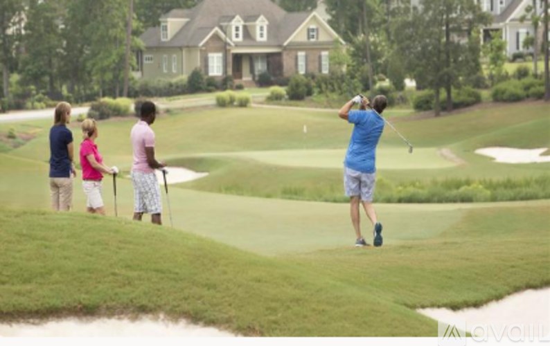 A man is playing golf in front of a house.