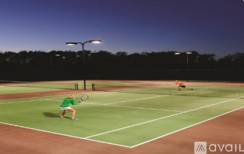 A woman in a green shirt is playing tennis on a court.