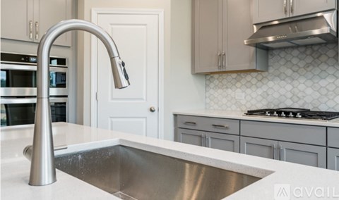 A modern kitchen with a stainless steel sink and faucet.