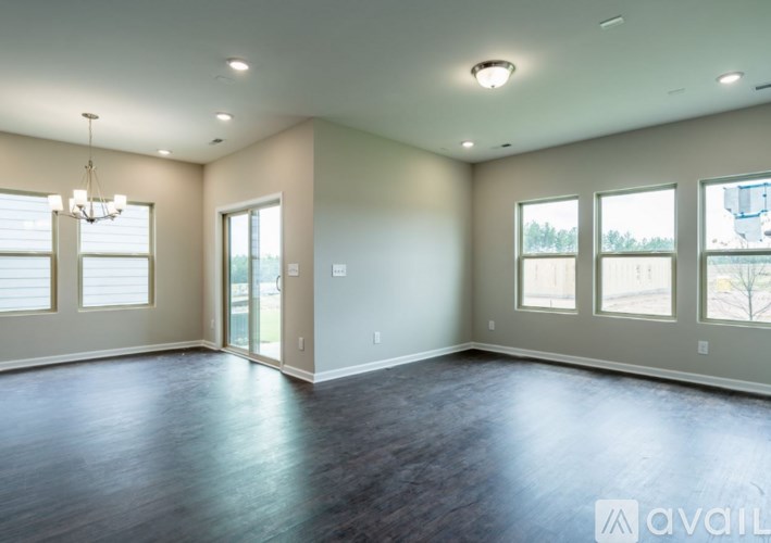 A spacious room with wood flooring and large windows.