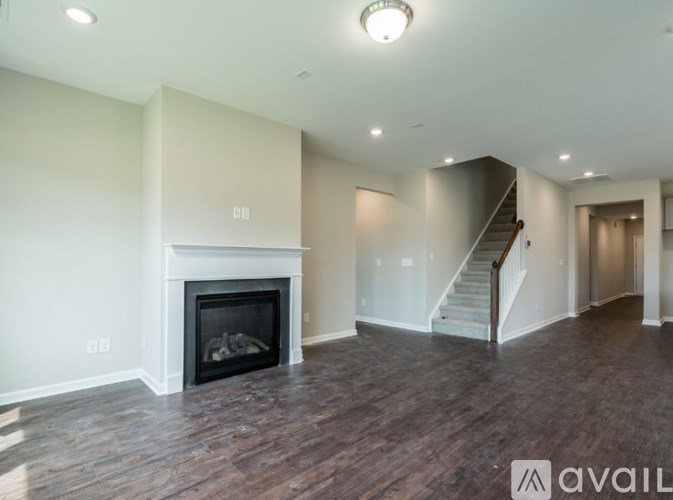 A spacious living room with a fireplace and a staircase.