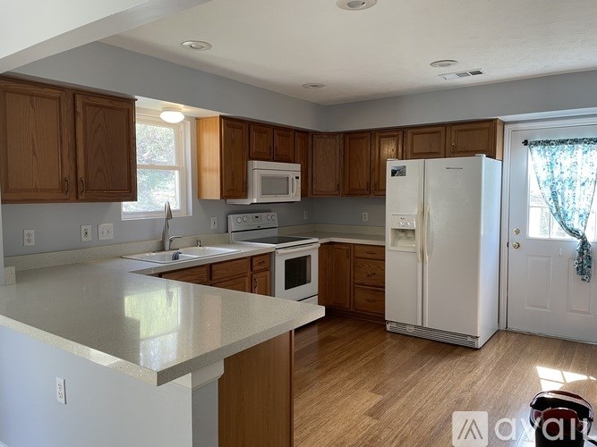 A kitchen with white appliances and wooden cabinets.