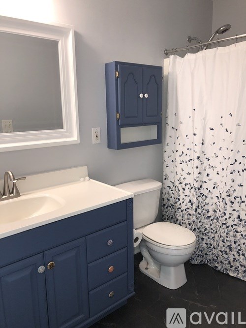 A white sink is in a blue cabinet in a bathroom.