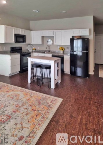 A kitchen with a black refrigerator and white cabinets.