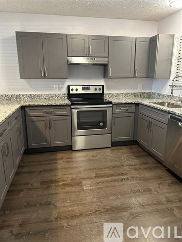 A kitchen with a stove top oven and wooden floors.