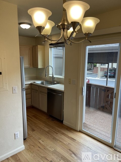 A kitchen with a refrigerator, sink, and wooden floors.